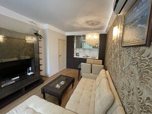 Relax in this stylish living room with a flat-screen TV, comfortable sofa, and modern kitchen area.