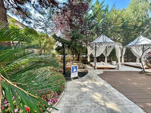 Relax in a serene garden setting with a shaded gazebo and nearby pool.