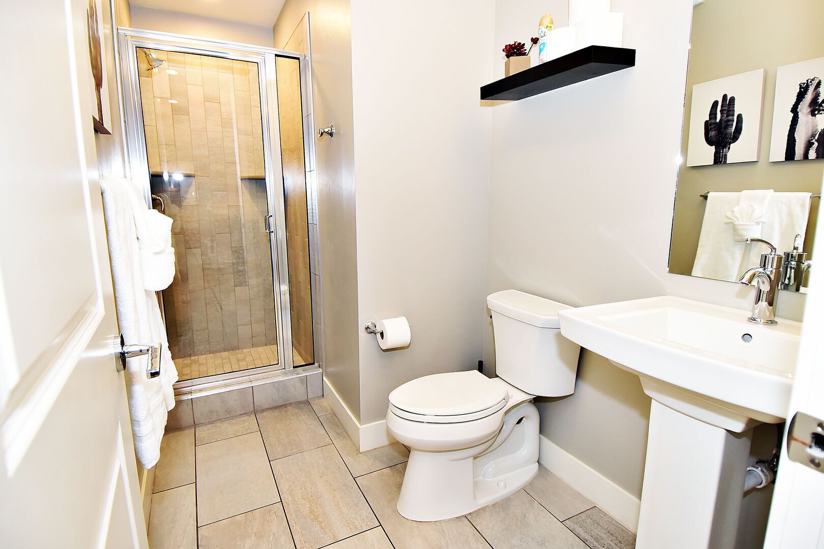 A bathroom with a shower, toilet, sink, and a mirror.
