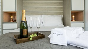 Un dormitorio ordenado con cama, mesitas de noche, una botella de Chandon, dos copas, una bandeja con uvas y una toalla con el texto 'Brazilian Corner'.