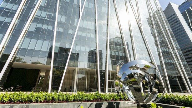 Un edificio moderno de vidrio con una escultura reflectante en primer plano.