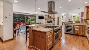 Une cuisine moderne dotée d’un grand îlot central, d’appareils électroménagers en acier inoxydable et de meubles de rangement en bois.