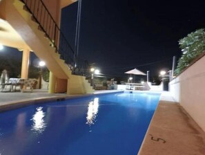 Relax by the pool, surrounded by comfortable seating and a staircase leading to additional facilities.