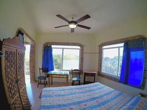 Relax in this inviting room with a large bed, ceiling fan, and two windows.