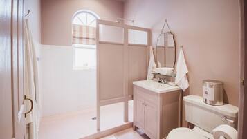 A bathroom with a shower, toilet, sink, and vanity.