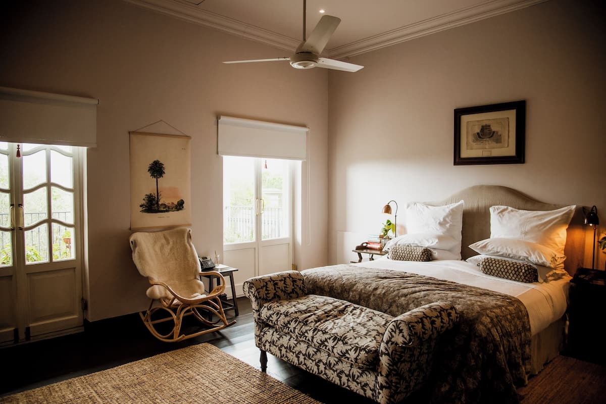 A bedroom with a bed, a rocking chair, a desk, and a framed picture on the wall.