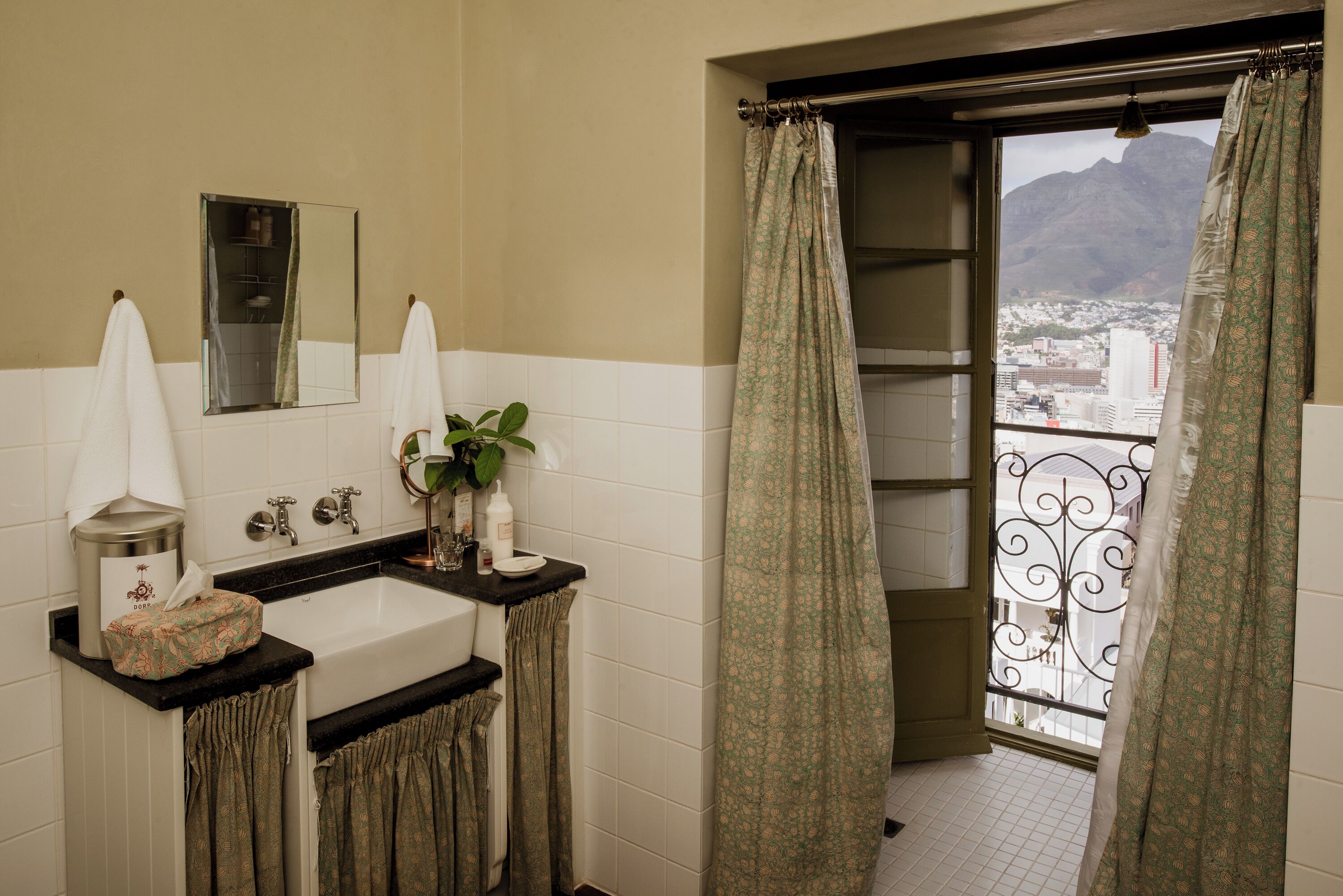 A bathroom with a large window, a sink, a mirror, and a plant.