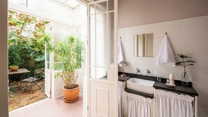 A bathroom with a large window, a sink, a mirror, and a potted plant. - Dorp Hotel (Cape Town)