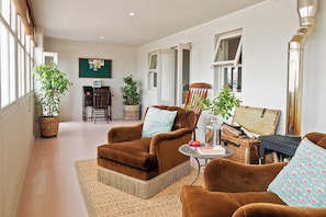 A cozy living room with brown sofas, a coffee table, and potted plants.