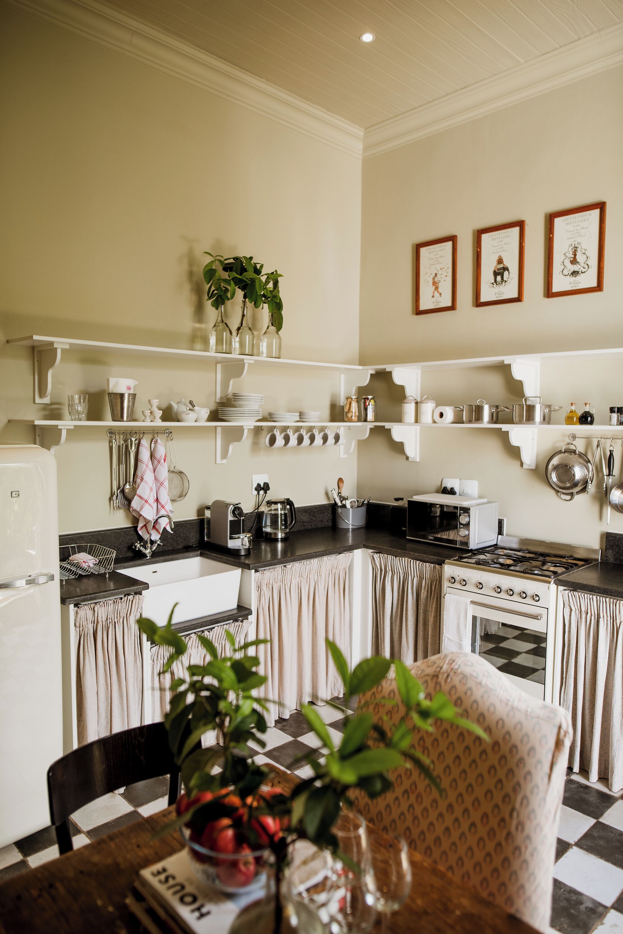 A kitchen with white cabinetry, a stove, and a dining area with a checkered tablecloth.