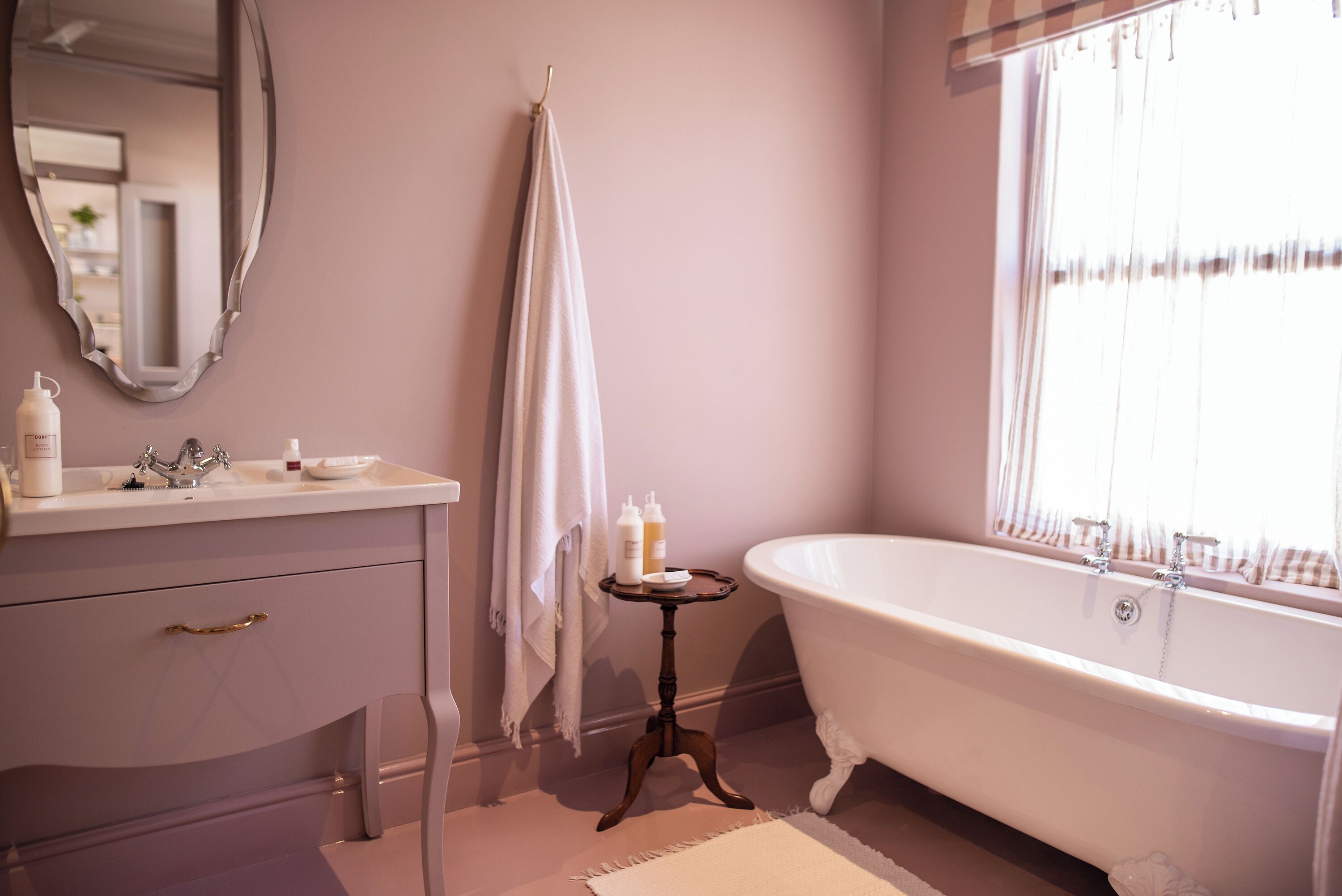 A bathroom with a freestanding bathtub, a vanity with a mirror, and a small table with toiletries.