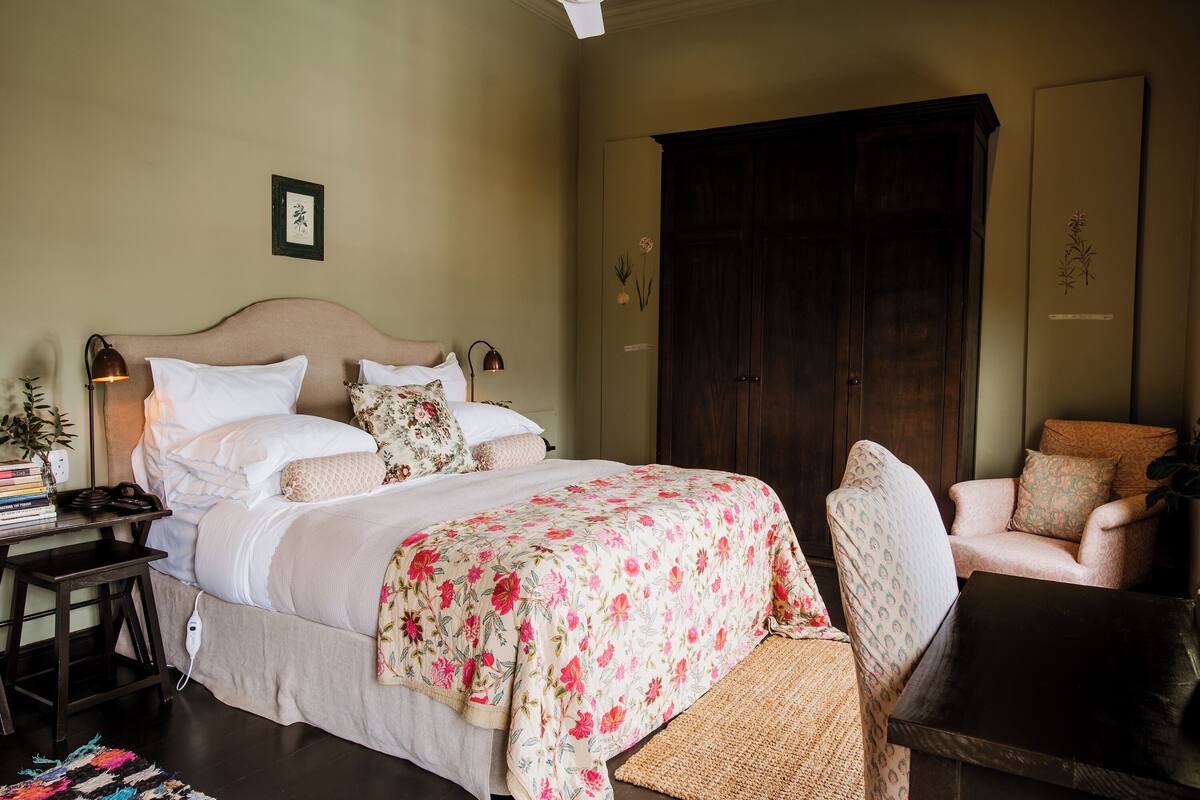A bedroom with a bed, bedside table, lamp, chair, and wardrobe.