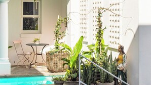 A white building with a balcony, a pool, and potted plants. - Dorp Hotel (Cape Town)