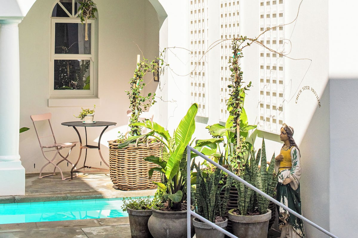 A white building with a balcony, a pool, and potted plants.