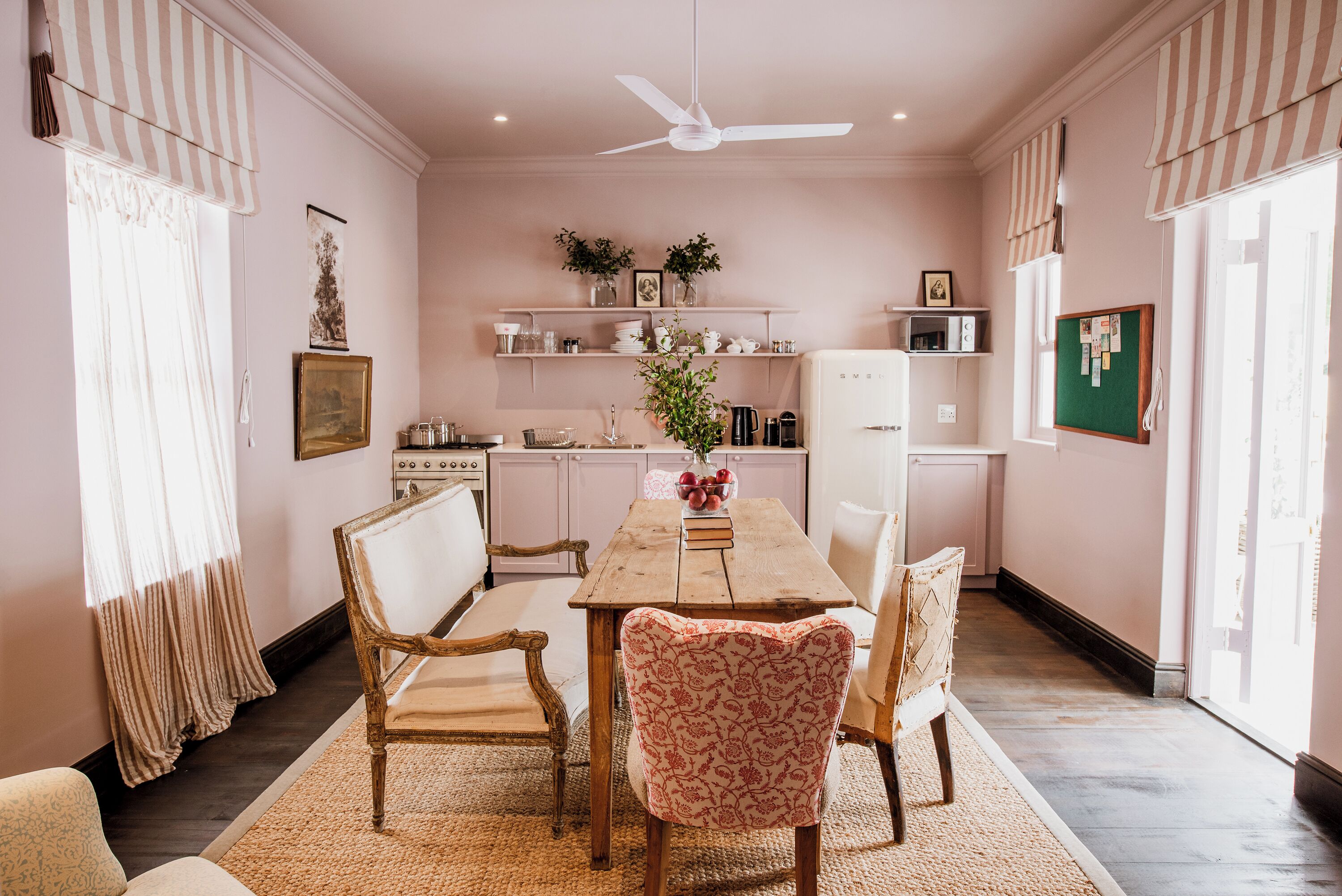 A dining area with a wooden table, four chairs, and a ceiling fan.