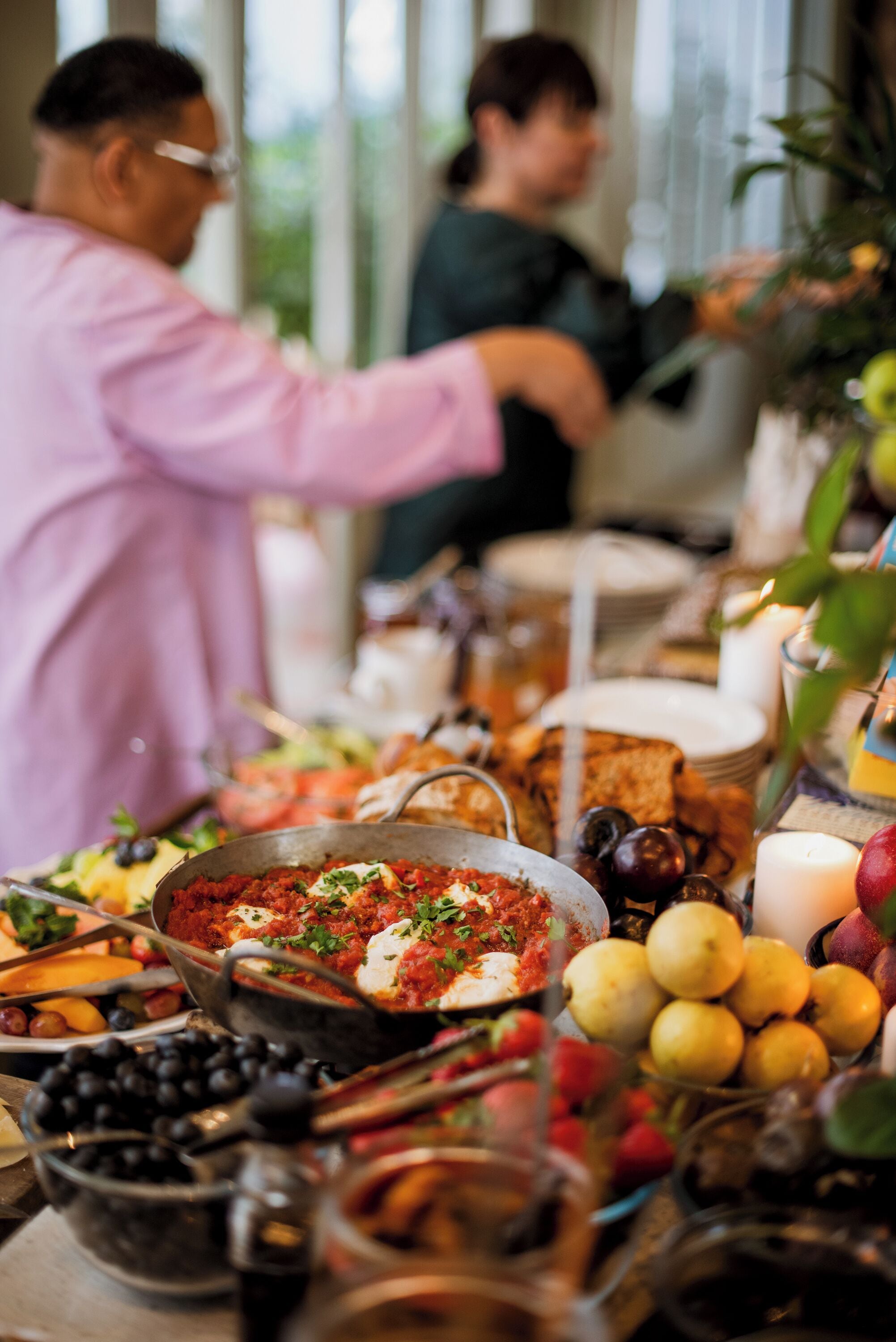 A buffet table with various dishes and fruits.