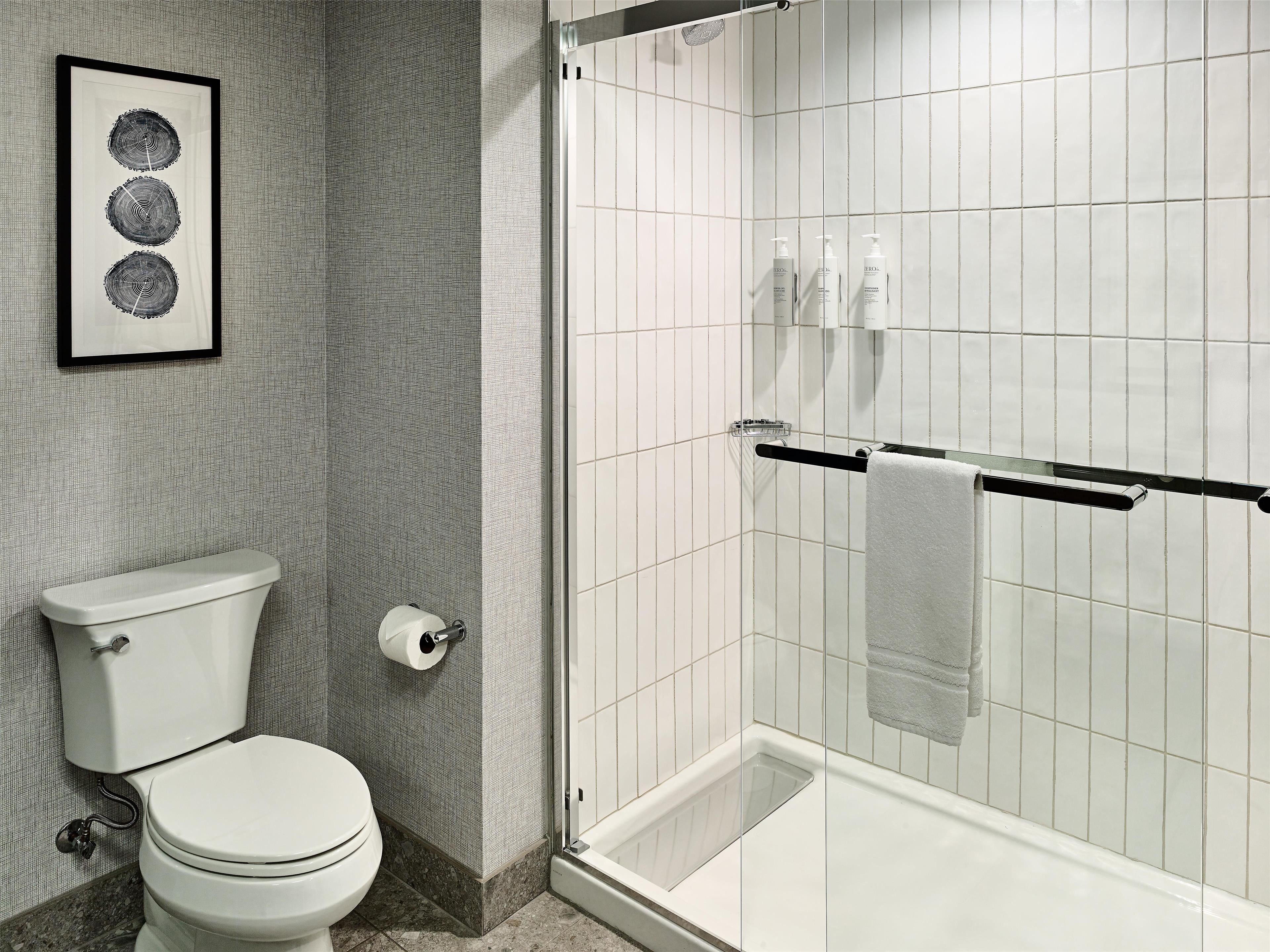 A bathroom with a toilet, a shower with a glass door, and a towel rack.