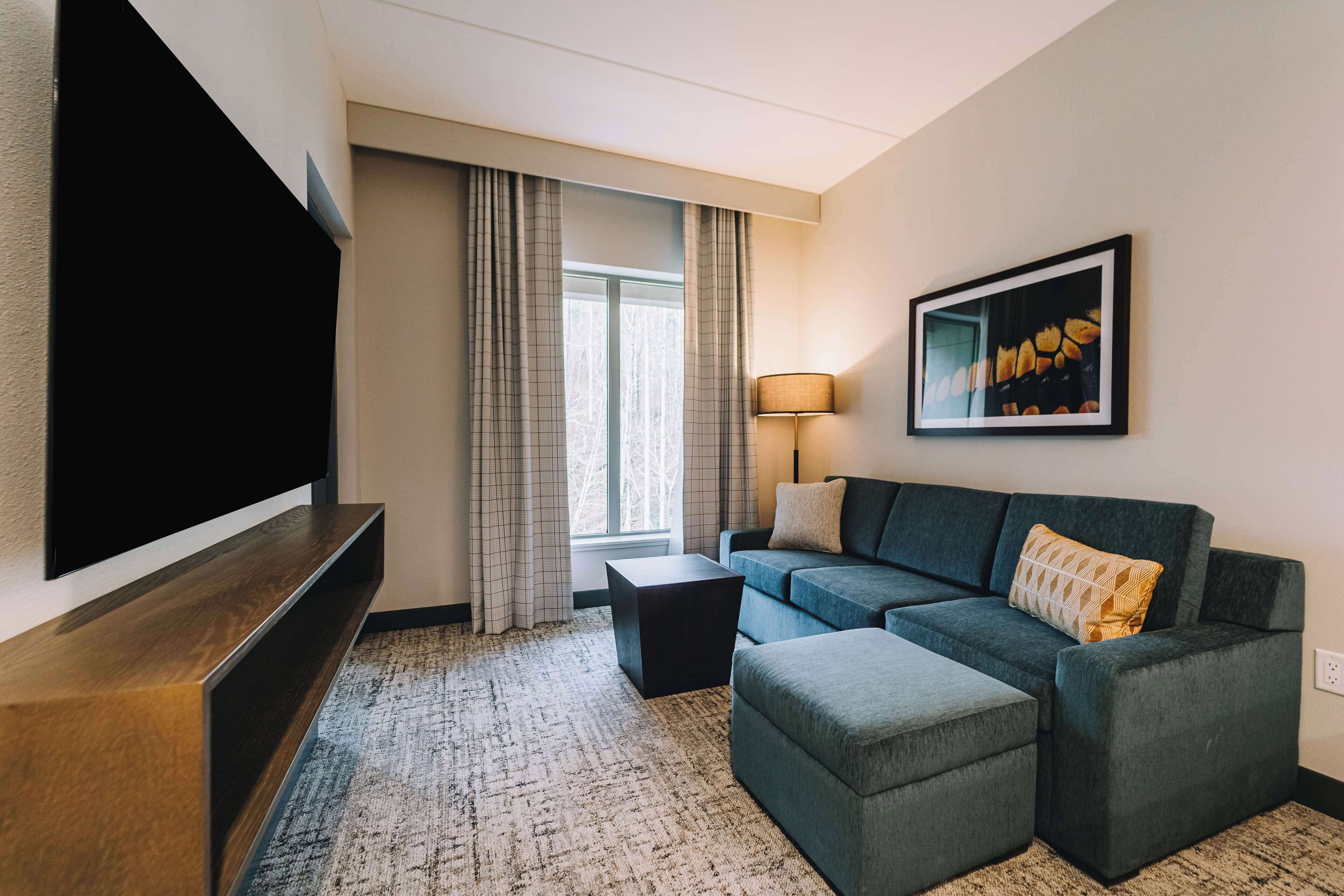 A modern living room with a sectional sofa, a flat-screen TV, a coffee table, and a patterned carpet.