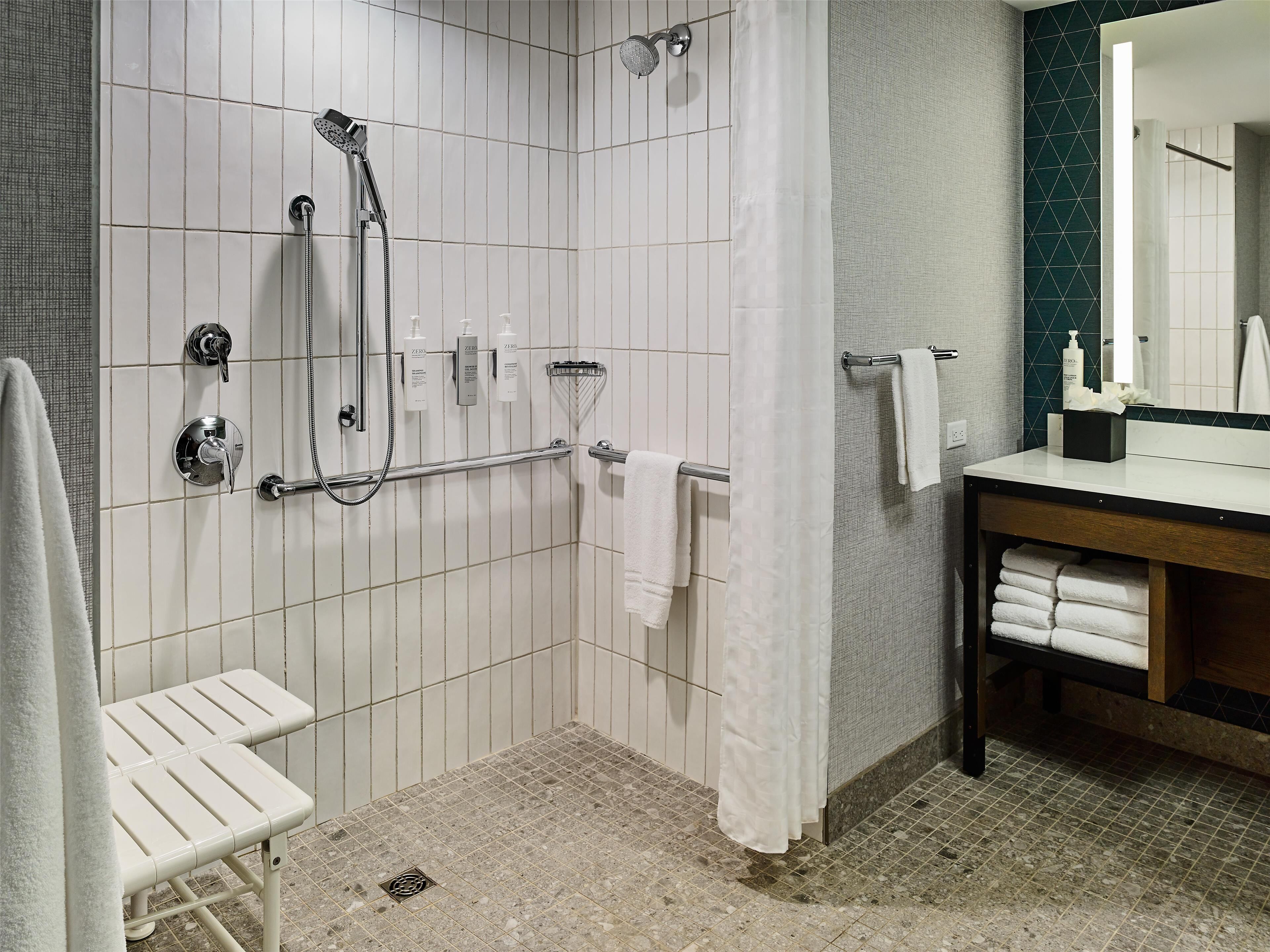 A modern bathroom with a shower, a toilet, a sink, and a mirror.
