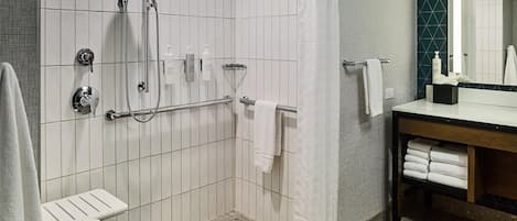 A modern bathroom with a shower, a toilet, a sink, and a mirror.