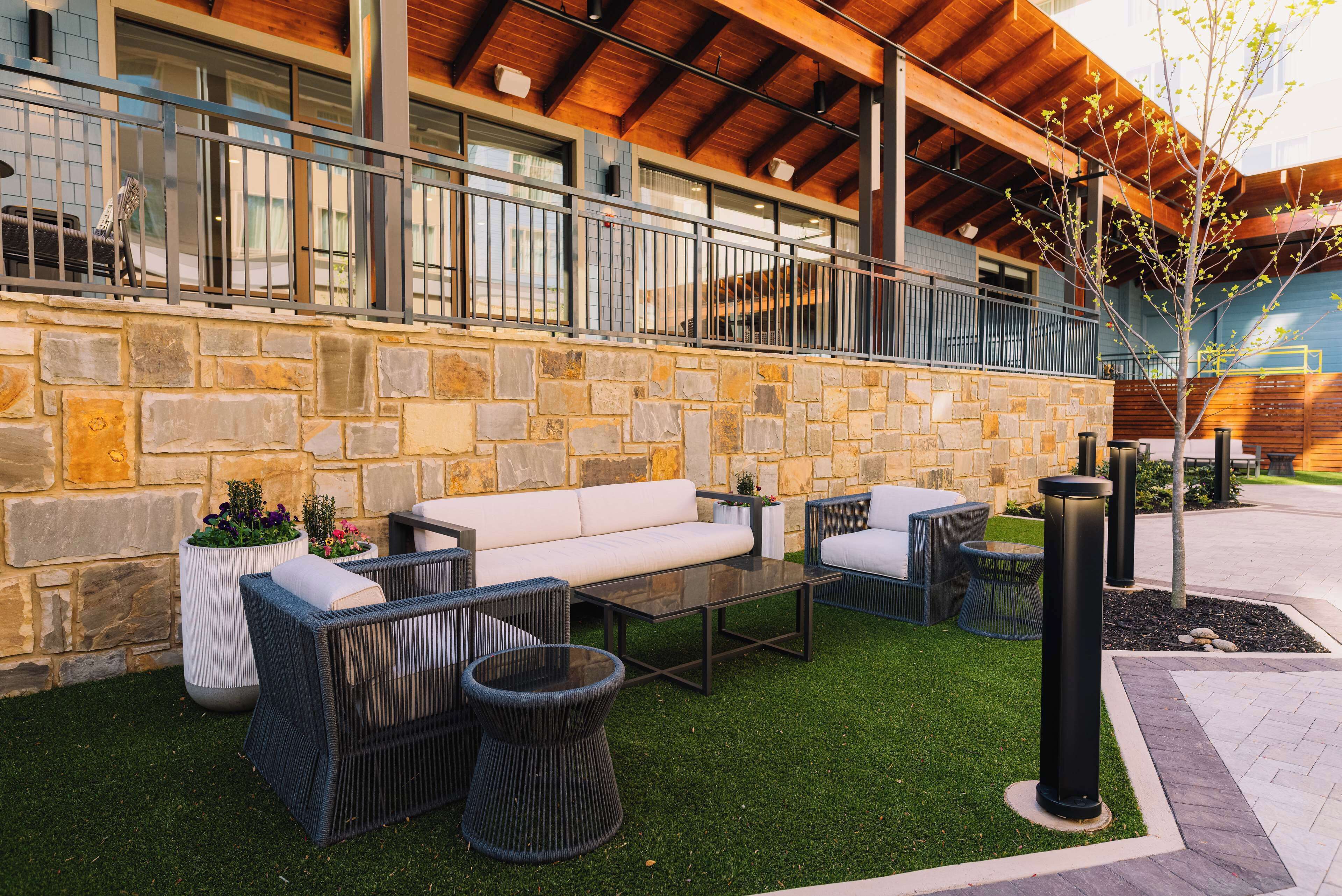 An outdoor seating area with stone walls, a wooden ceiling, and a small tree.