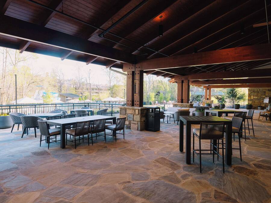 An outdoor patio area with stone flooring, wooden beams, and tables and chairs.