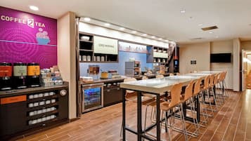 A coffee shop with a long counter, a trash bin, and a sign that says "Good Morning".