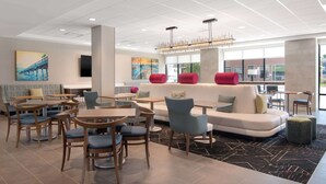 A modern hotel lobby with a seating area, tables, and artwork on the walls.