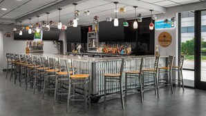 A bar area with a long counter, multiple hanging light fixtures, and a variety of bottles.