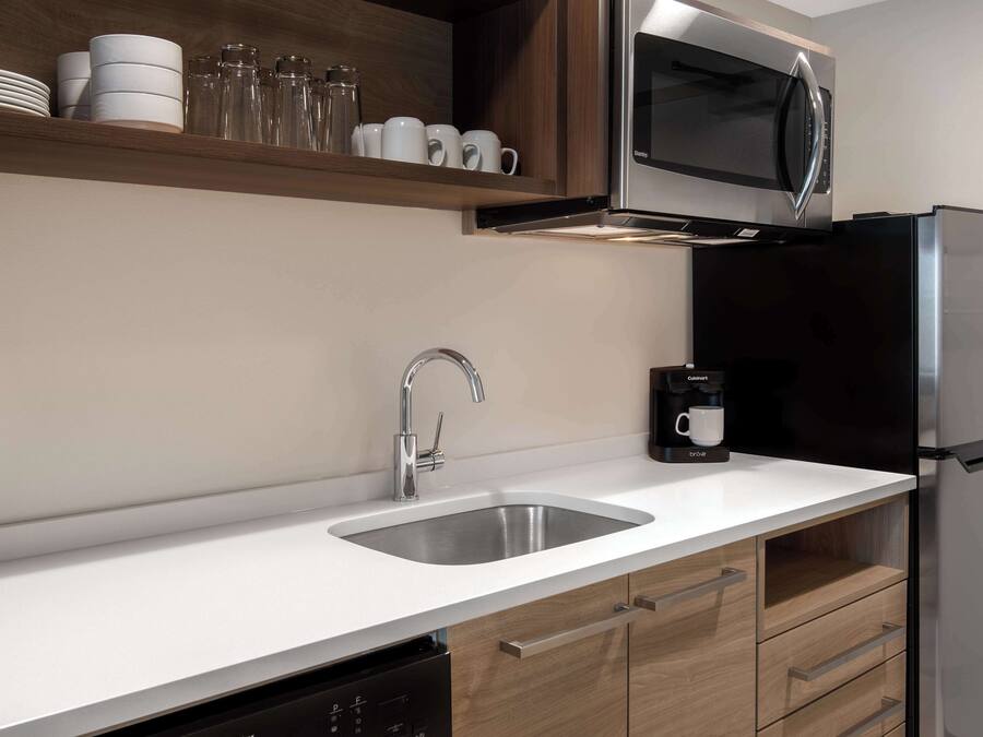 A modern kitchen with a stainless steel sink, a microwave, and a black refrigerator.