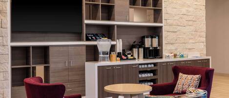 A modern living area with a TV, built-in shelves, a coffee machine, and seating.