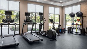 Un gimnasio con cintas de correr, elípticas y pelotas de ejercicio.