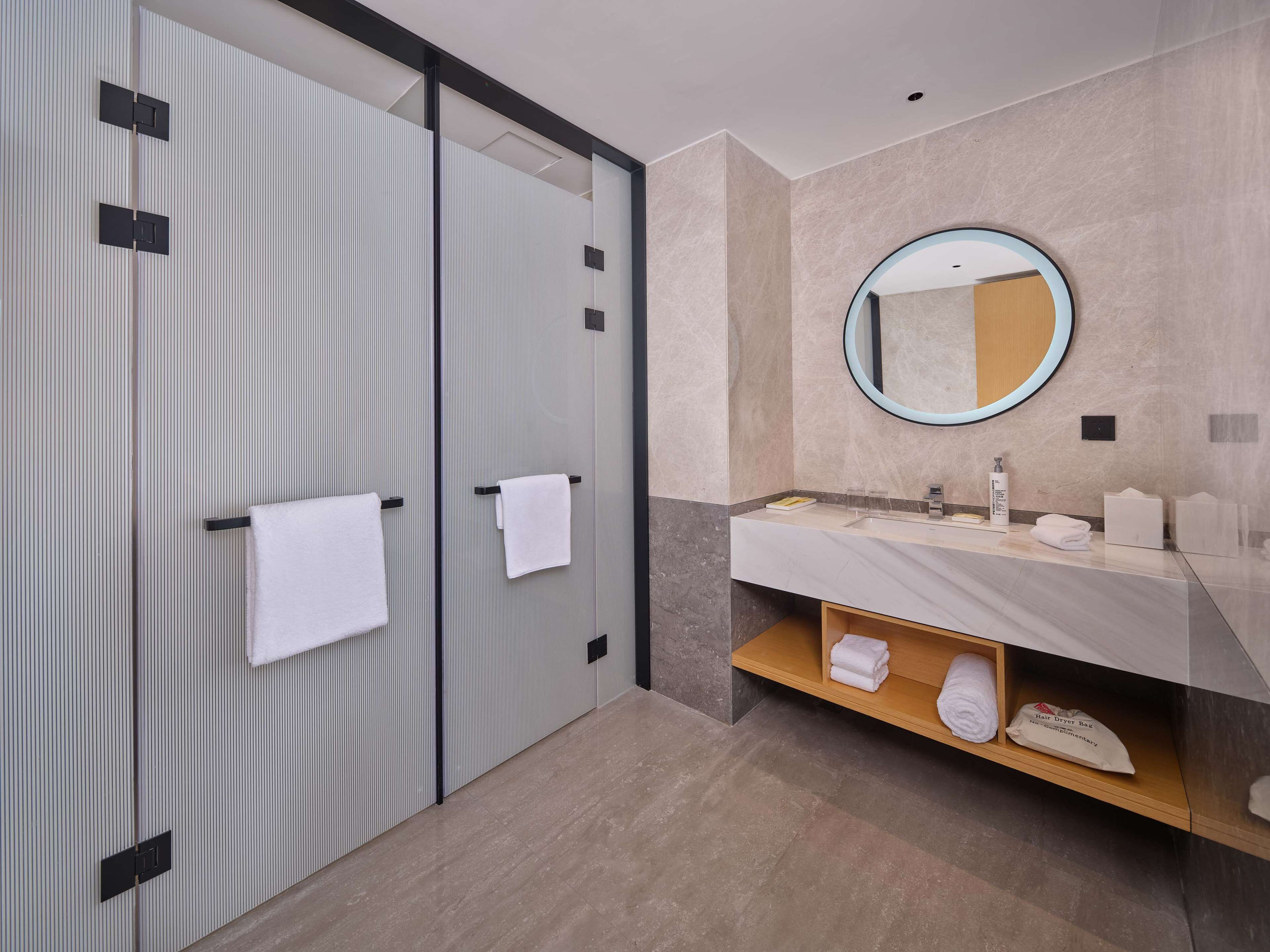 Une salle de bain moderne avec un grand miroir, un lavabo et deux porte-serviettes.
