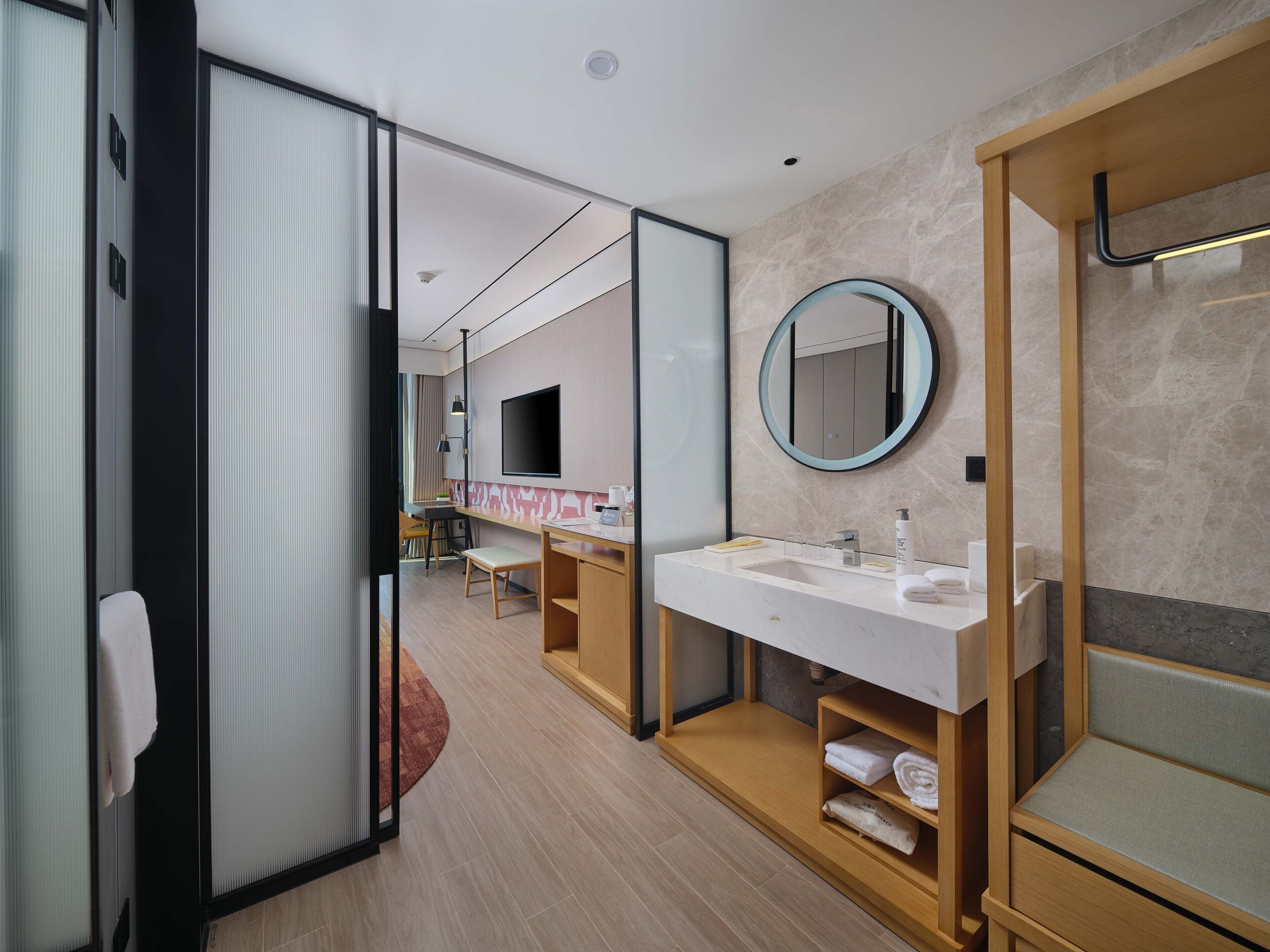 A modern hotel bathroom with a large mirror, a sink, and a shower area.