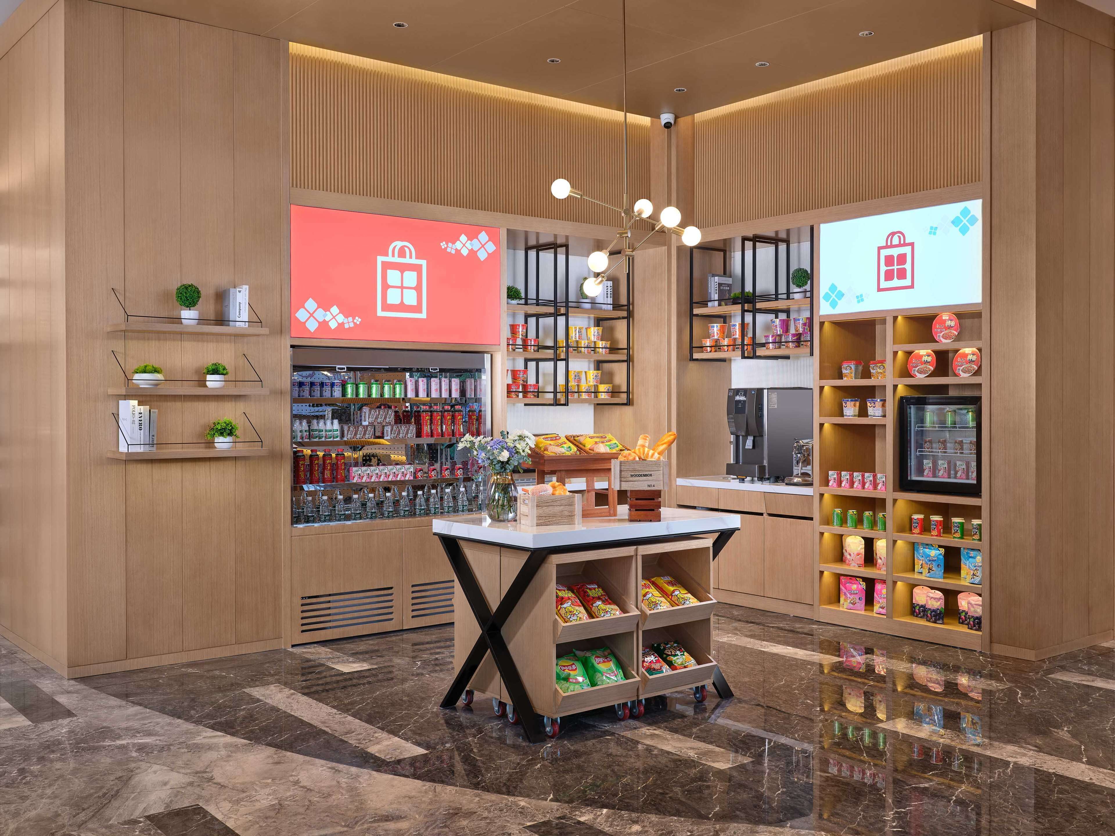 A modern retail space with wooden paneling, a central display table with snacks, and shelves stocked with various products.
