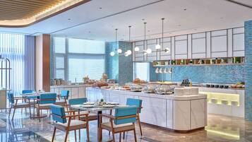 A modern hotel lobby with a central island, seating area, and a blue-tiled backsplash.