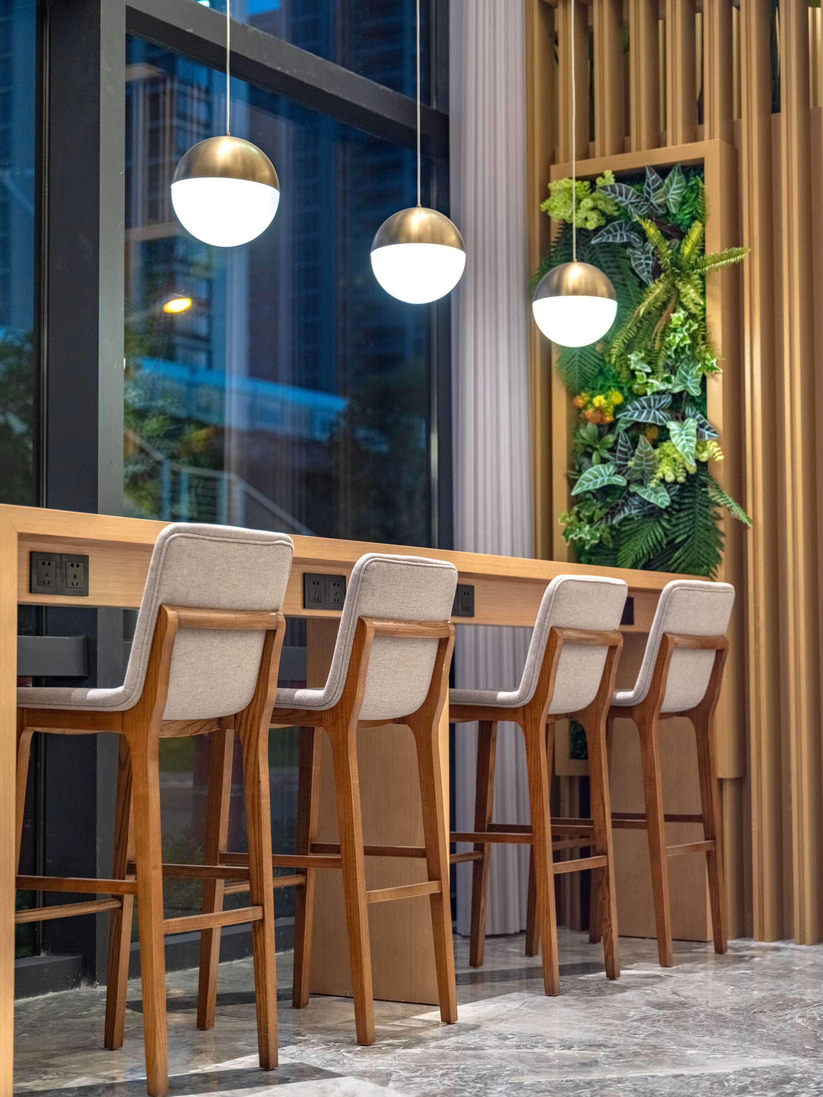 A modern bar area with wooden chairs and pendant lights.