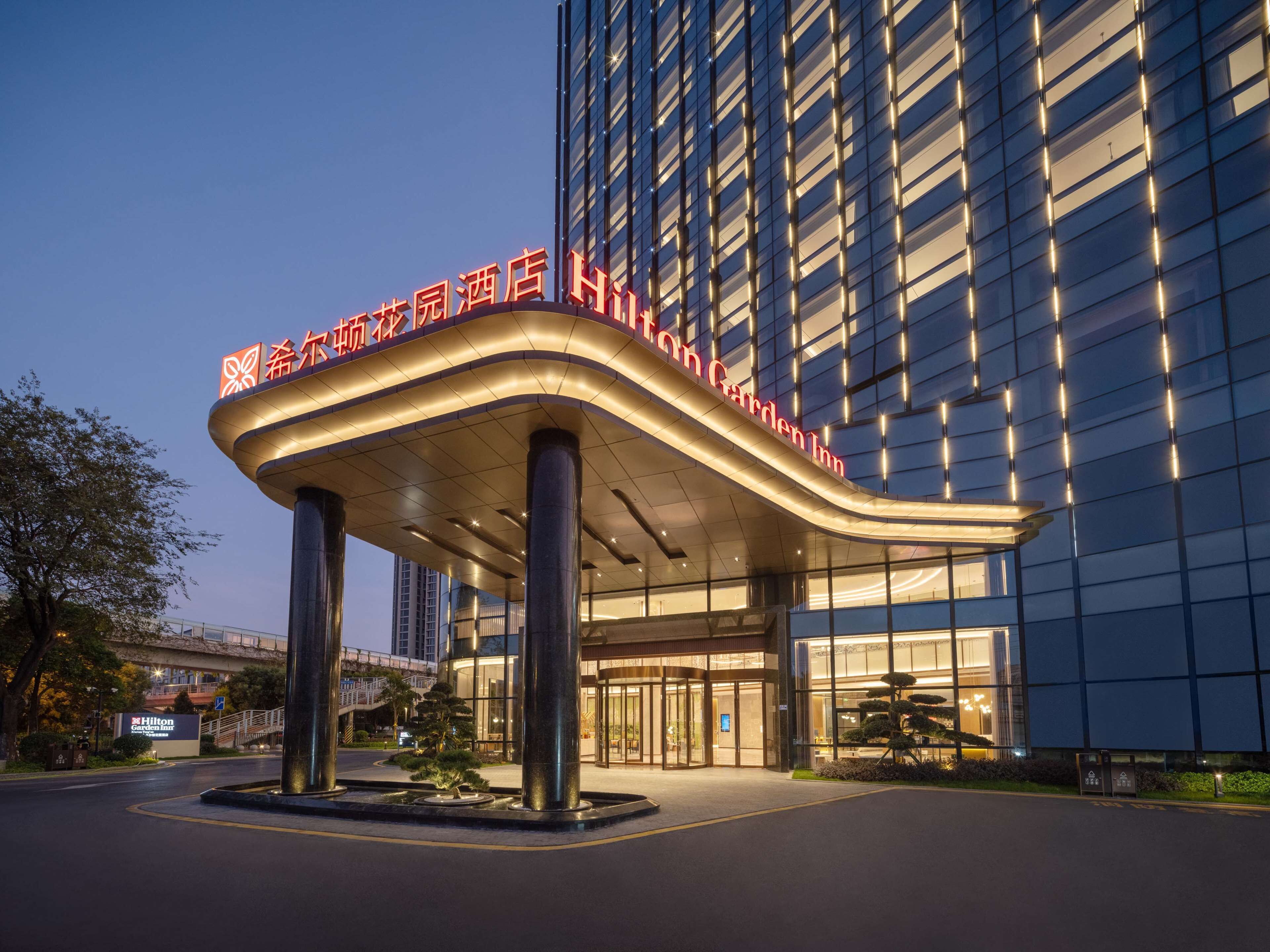 Une entrée d’hôtel moderne, dotée d’un auvent incurvé et d’une enseigne lumineuse.