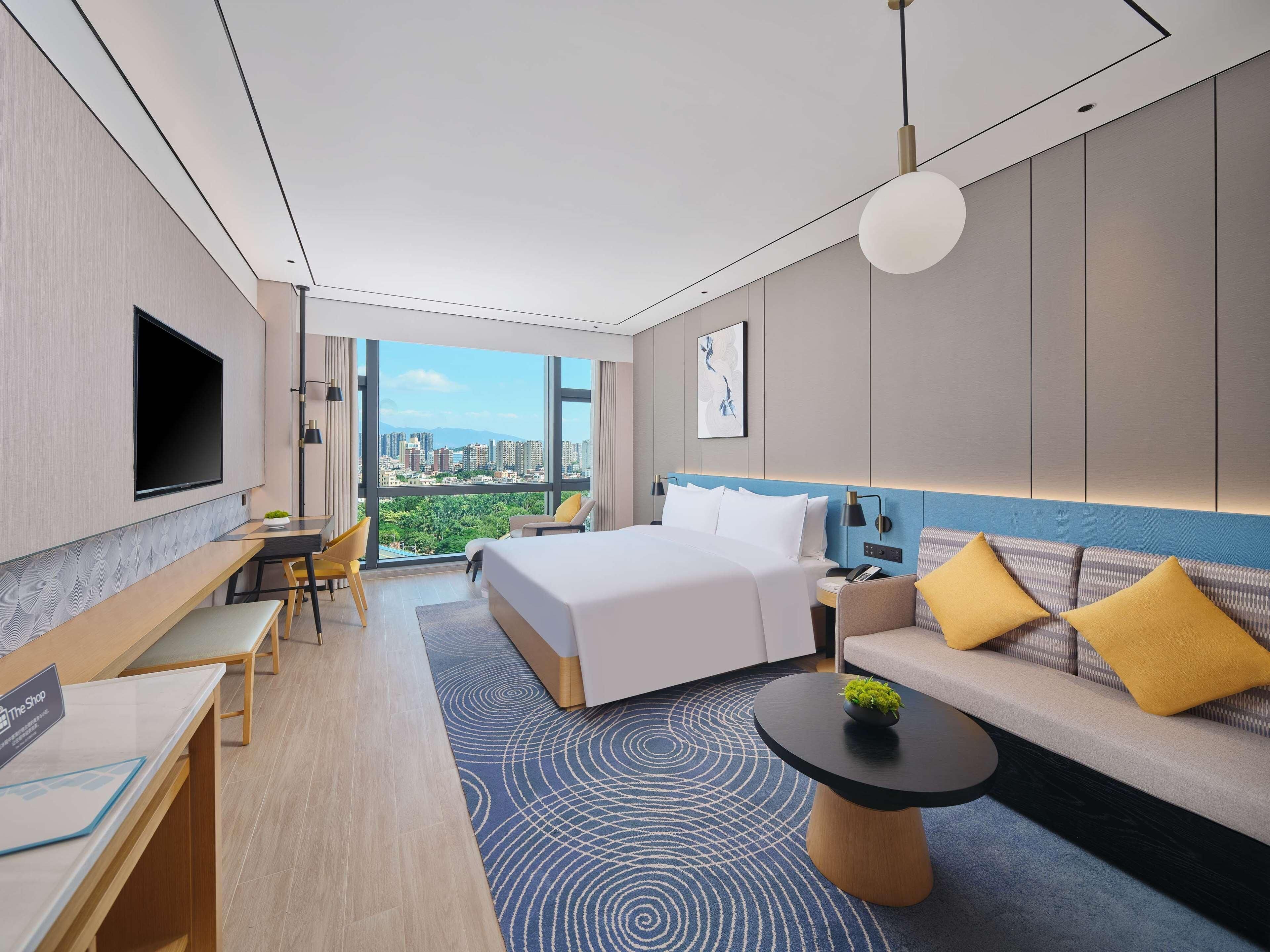 Una habitación de hotel moderna con una cama grande, un sofá, un escritorio y un televisor.