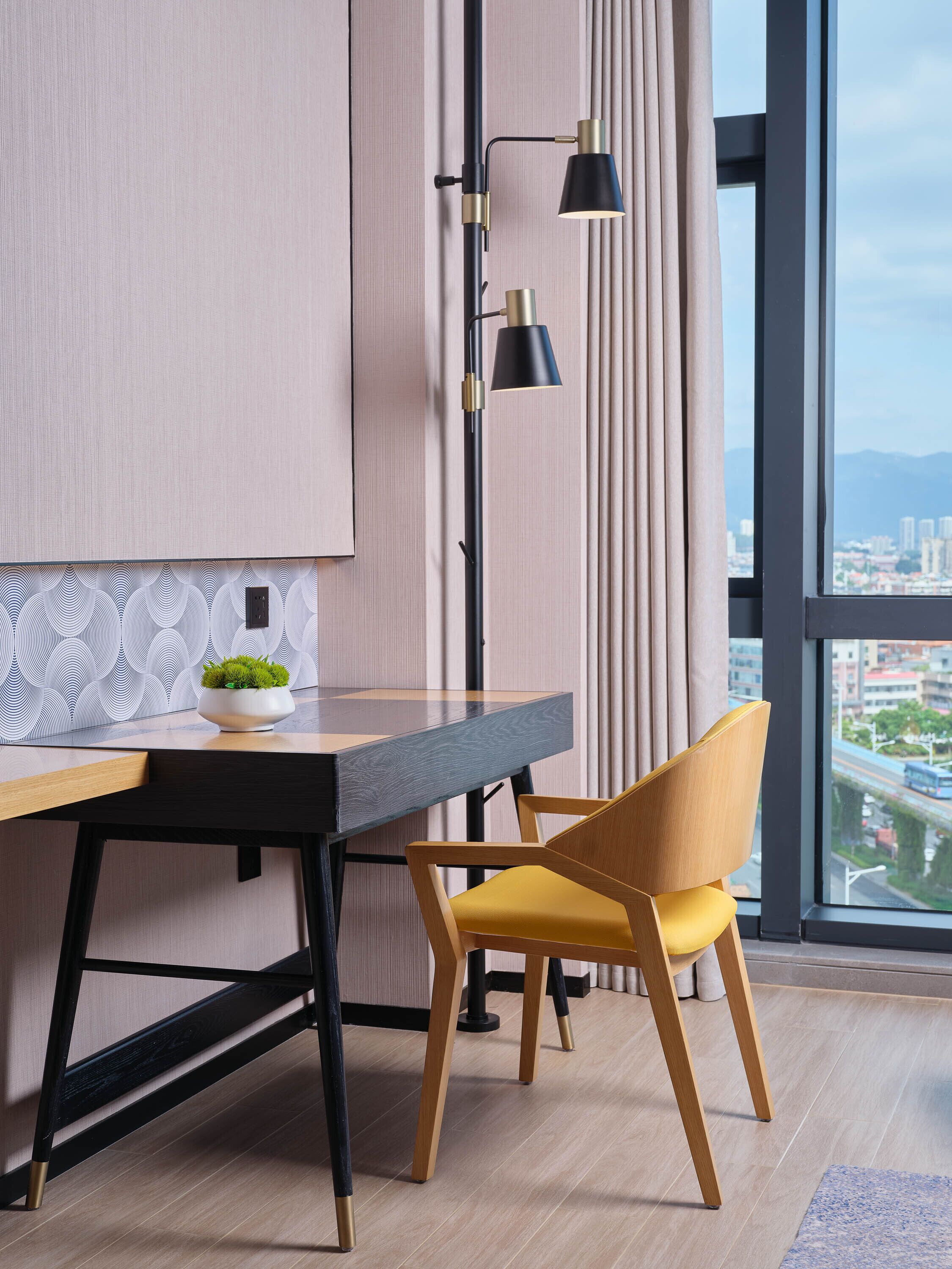 Un comedor moderno con una mesa de madera, una silla amarilla y una lámpara de pie negra.