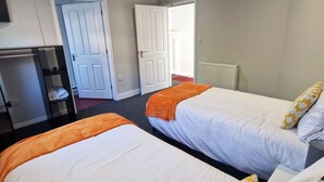 Ett hotellrum med två sängar, ett skrivbord och ett element.