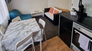 Ett kompakt hotellrum med ett matbord, en soffa, ett litet köksutrymme och en säng.