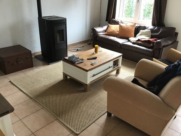 A living room with a sofa, a coffee table with magazines, a remote control, and a black heater.