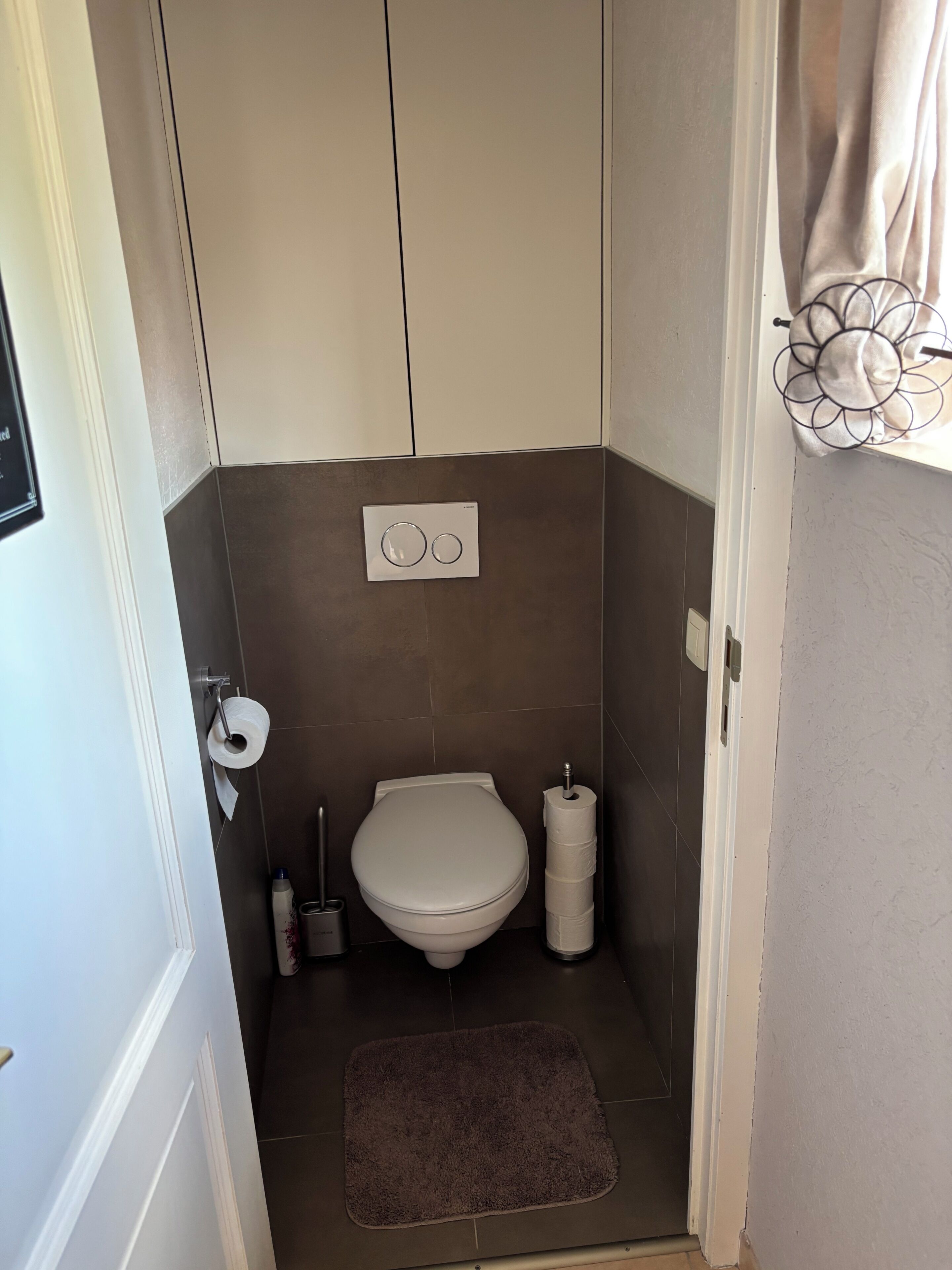 Ein kleines Badezimmer mit Toilette, Seifenspender und Toilettenpapierhalter.