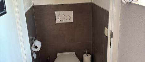 Ein kleines Badezimmer mit Toilette, Seifenspender und Toilettenpapierhalter.