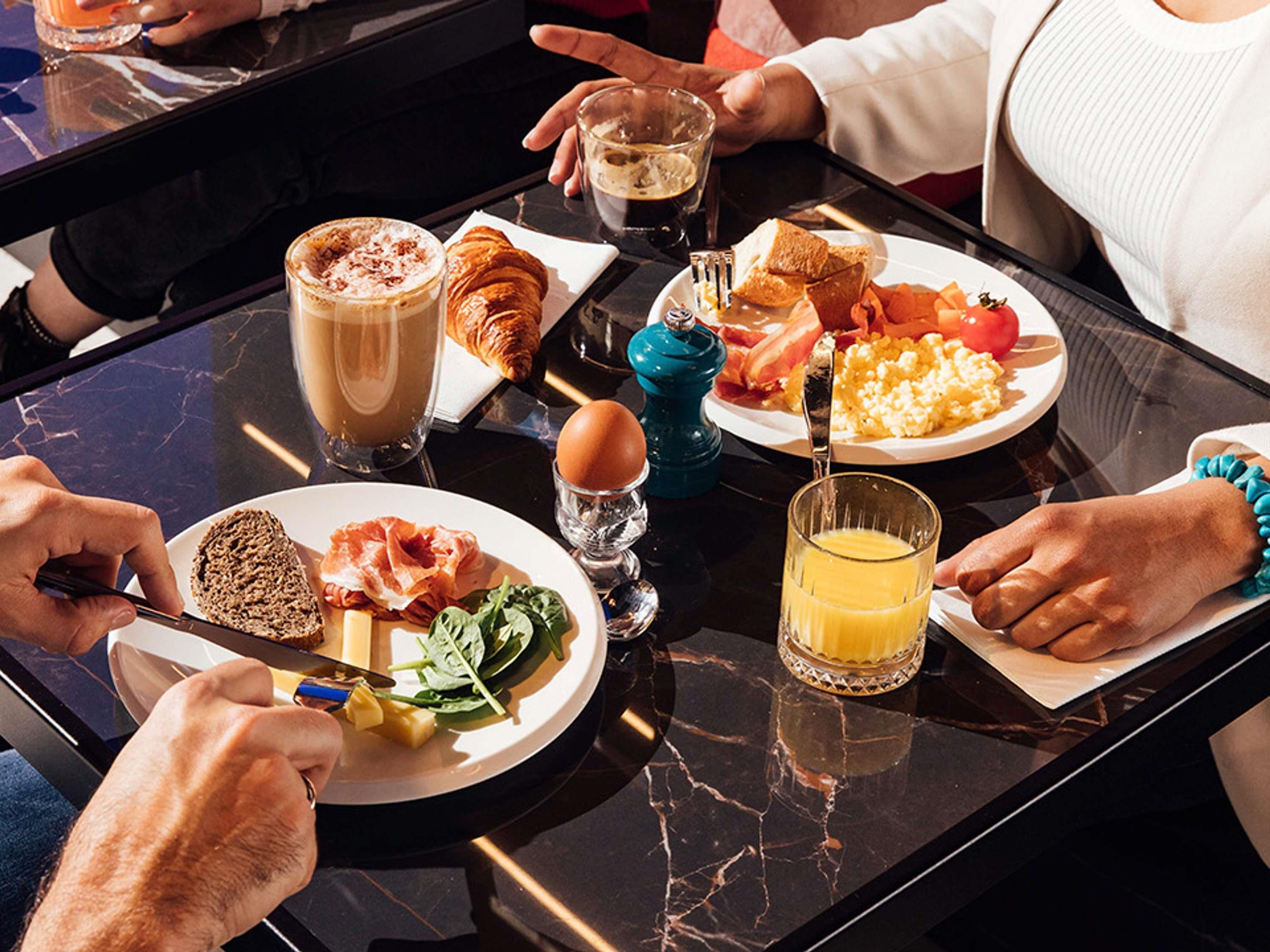 A breakfast setting with croissants, eggs, and a glass of orange juice on a marble table.