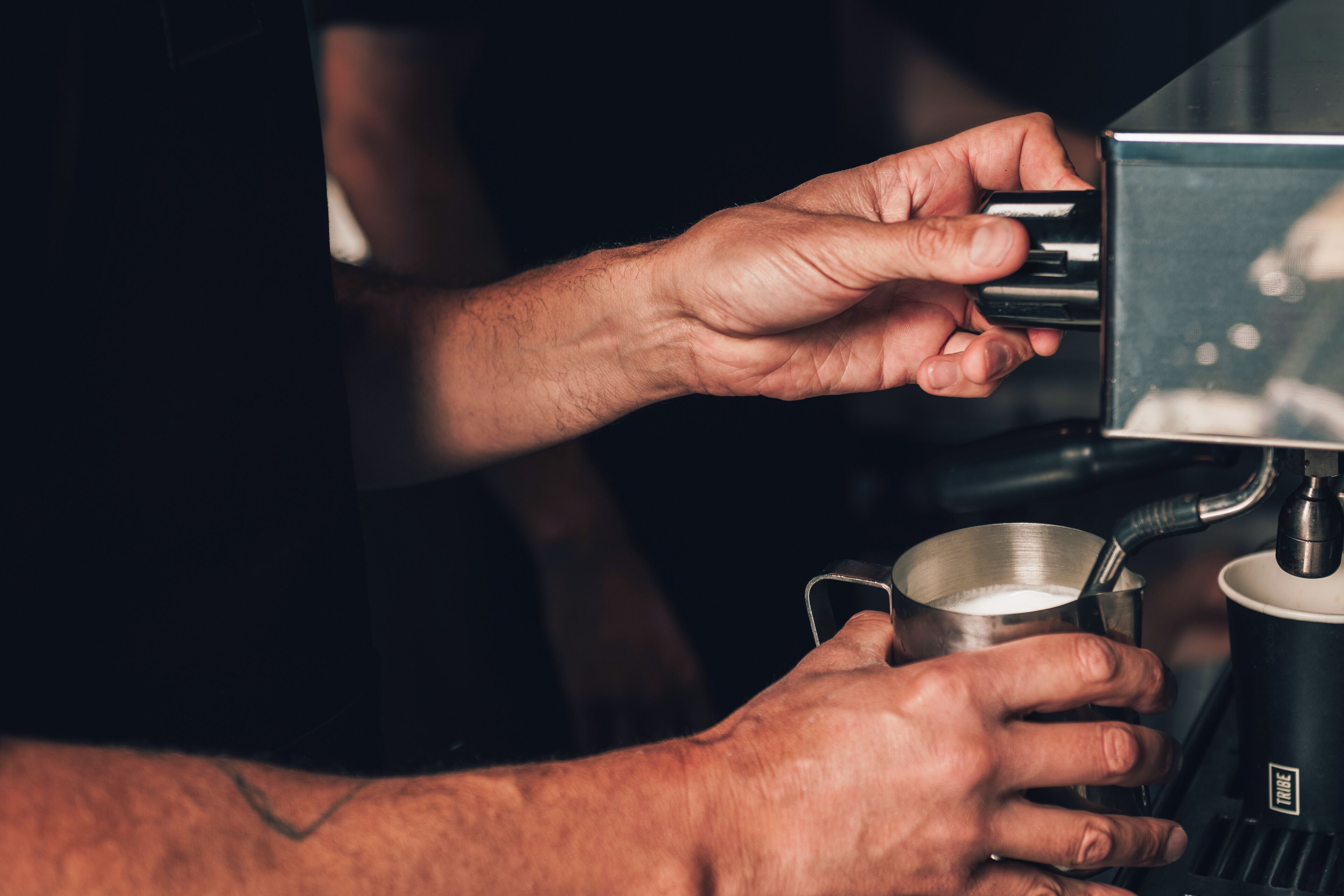 A person holding a cup of coffee from a machine.