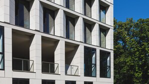 A modern building with a geometric facade, multiple balconies, and large windows.