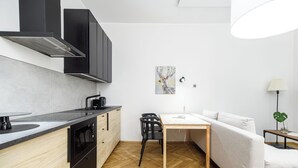 Ett modernt kök med en inbyggd ugn, ett matbord med stolar och en soffa i ett vardagsrum.