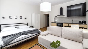 Ett modernt sovrum med en säng, en soffa, ett skrivbord och ett litet kök.